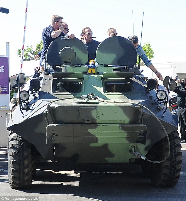 Getting tanked! Schwarzenegger seemed to be taking in the spectacle as he stood atop the camouflaged vehicle as it made its way through the prominent road