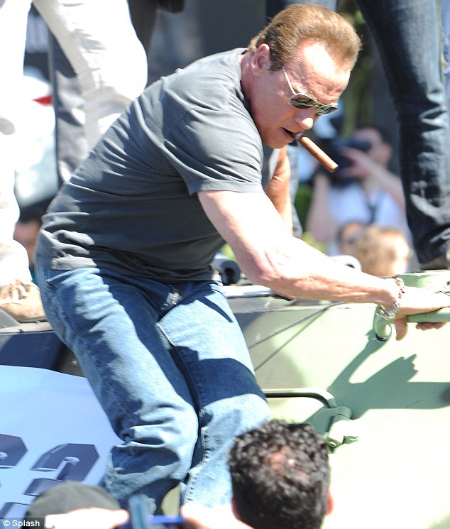 Keep cool! Arnold Schwarzenegger, 66, was seen exiting the military vehicle with a cigar in his mouth