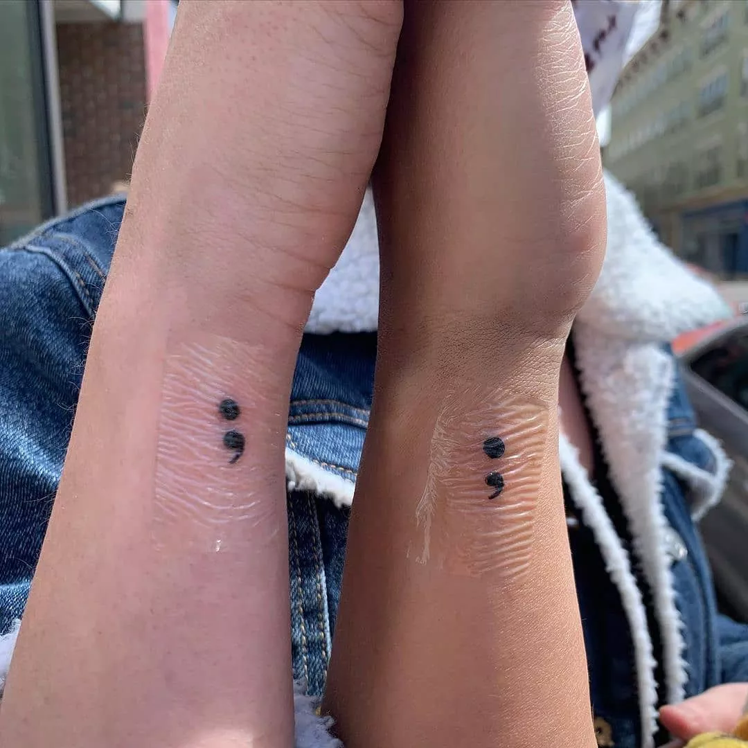 Close up of matching semi-colon tattoos on wrists