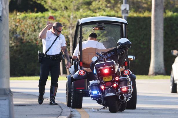 A barefoot DJ Khaled sulks as he receives a ticket while driving a golf cart