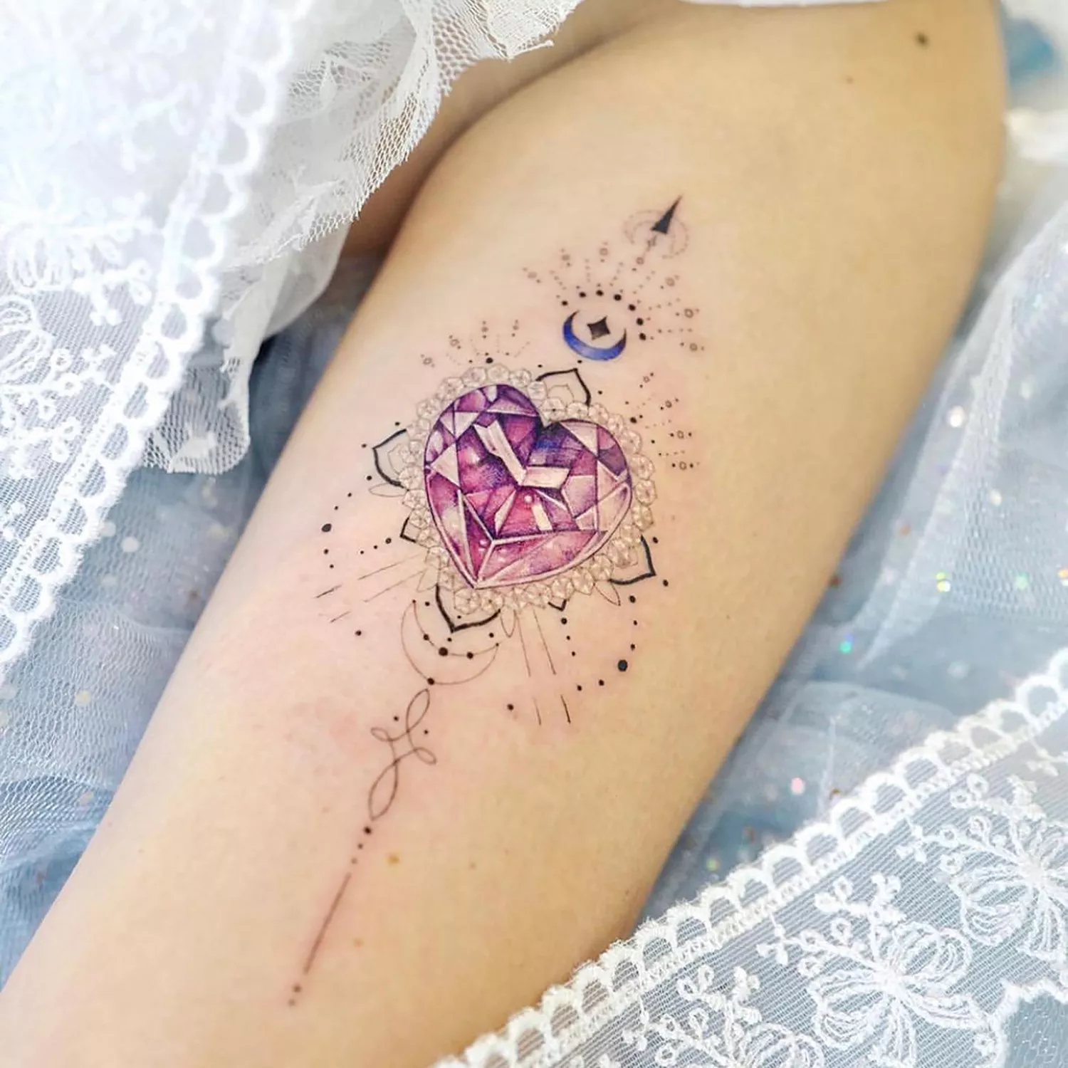 Close up of a heart-shaped gem tattoo on a leg