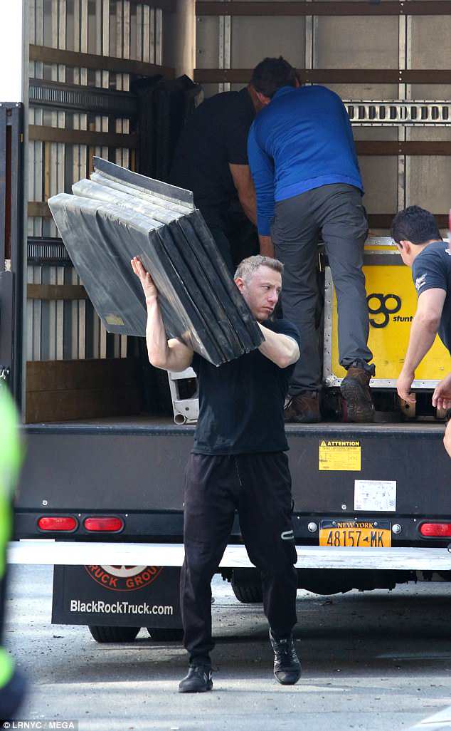 Manual labour: An assistant shouldered a batch of mats as they emptied the van on Thursday 