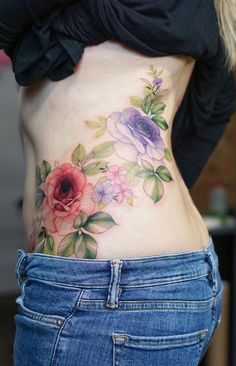 This may contain: a woman's stomach with flowers painted on the side and behind her is a black shirt