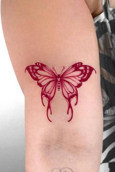 This may contain: a woman's arm with a red butterfly tattoo on the left side of her body