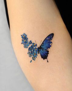 This may contain: a blue butterfly tattoo on the left thigh and right leg, with small flowers around it