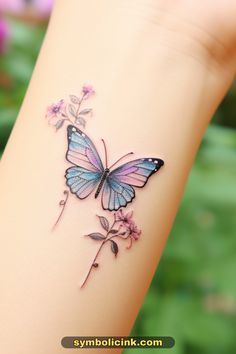 This may contain: a small butterfly tattoo on the wrist with pink flowers and green leaves around it's wings