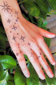 This may contain: a woman's hand with stars tattooed on it