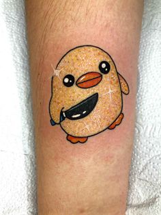 This may contain: a small cartoon character tattoo on the leg, with an orange bird and black beak