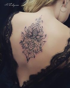 This may contain: the back of a woman's shoulder with an intricate tattoo design on her lower back