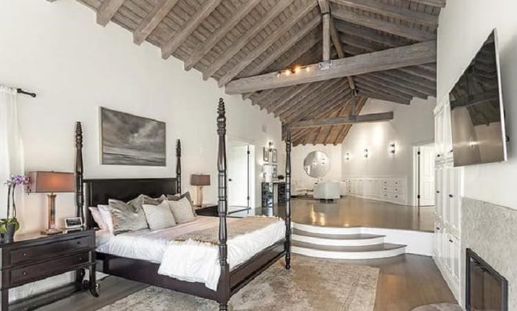 The primary bedroom inside Selena Gomez's house, with a four-poster bed underneath a beamed wood ceiling