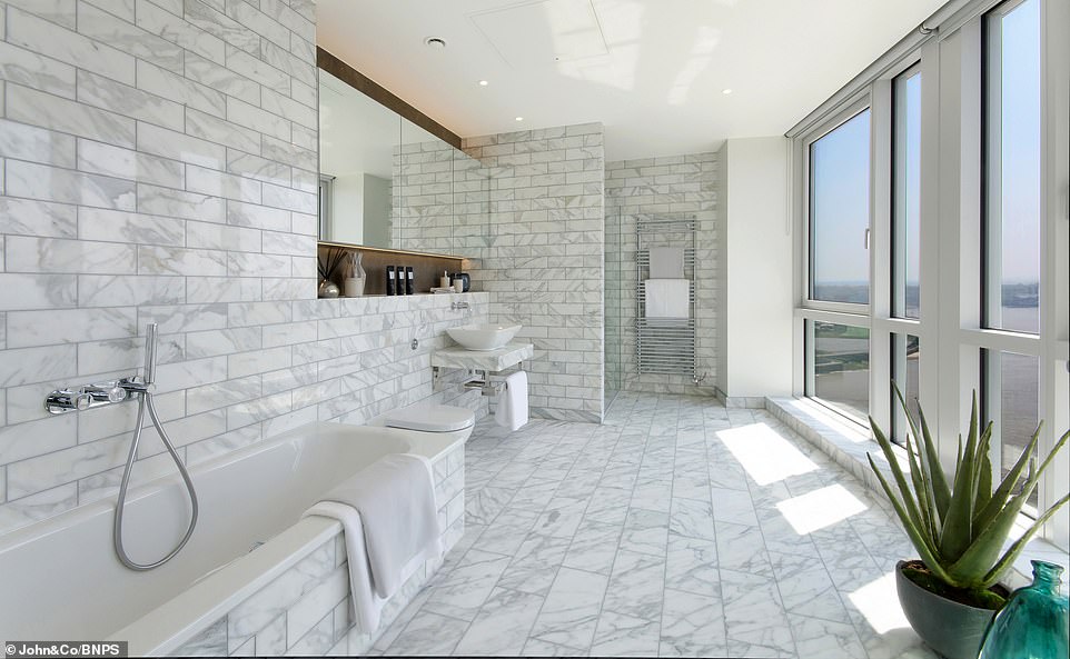 This is one of the luxury bathrooms - complete with floor-to-ceiling windows - at the penthouse, which boasts three bedrooms and has formerly been home to three international footballers